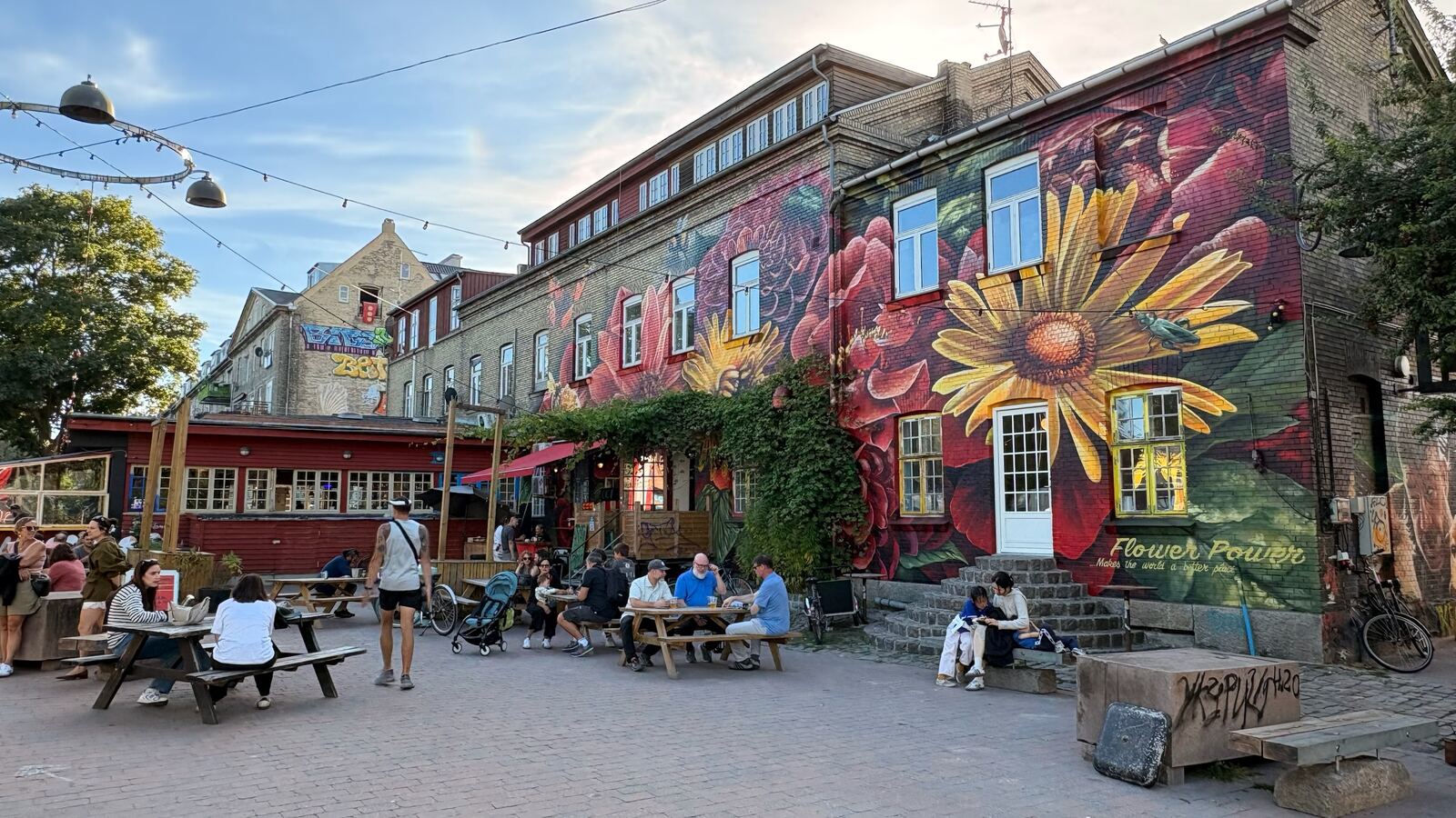 Mural de flores gigantes en Christiania, con gente en las mesas